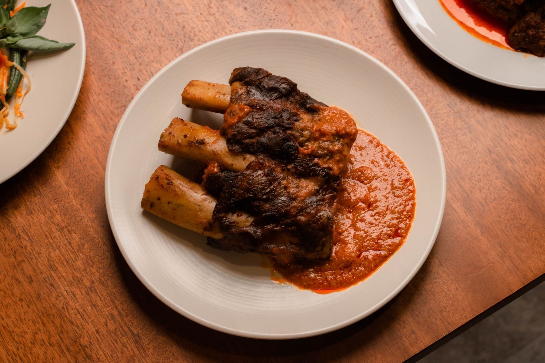 Bone-in braised short ribs in rich red sauce, plated dark