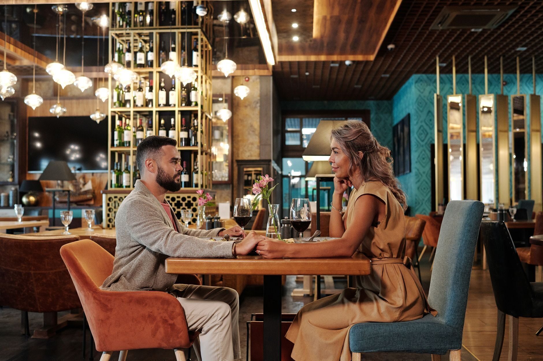 An upscale dining room with warm pendant light, an emerald wall accent and gold detailing